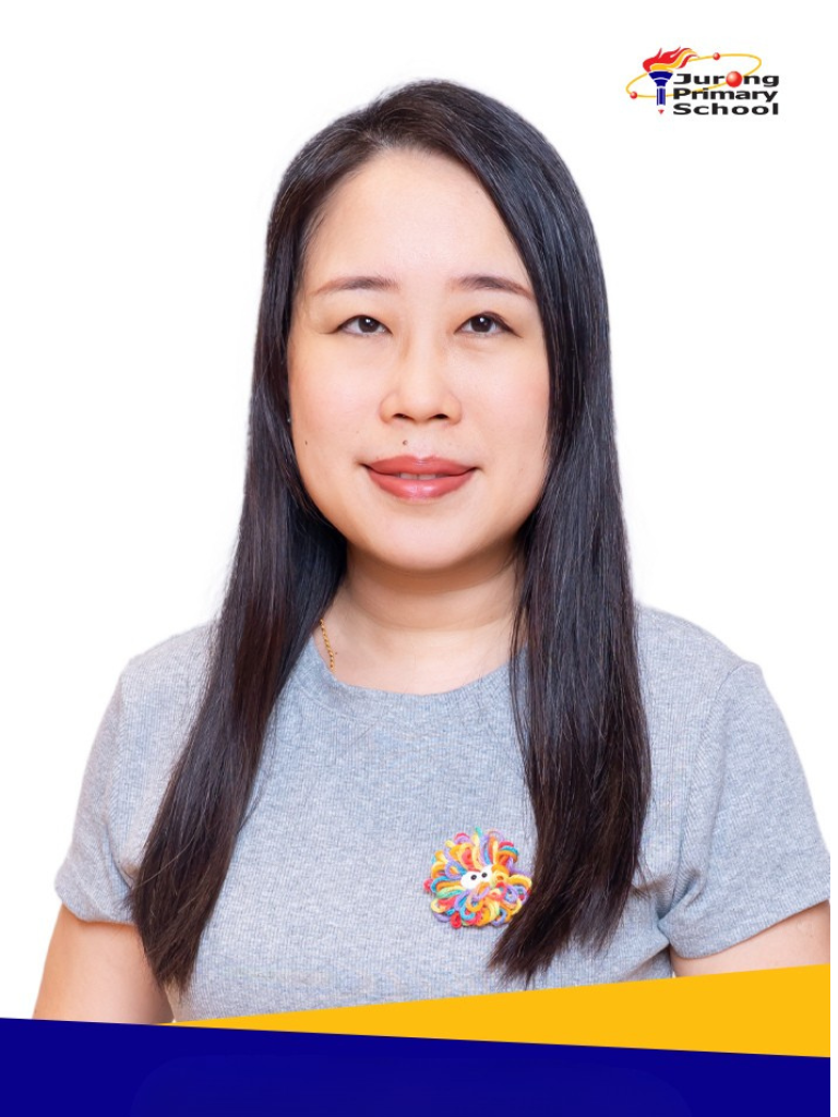 Woman in grey top, long straight black hair, colourful brooch